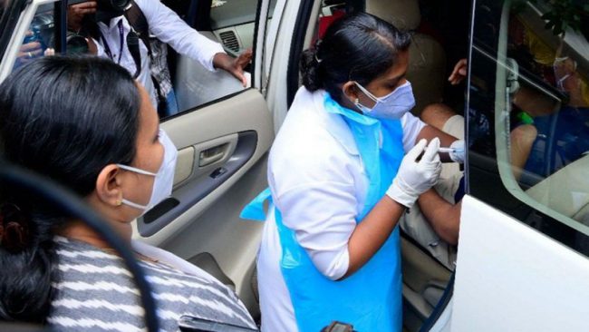 Drive-In-Vaccination_Kerala-Health-Minister-Looks-On.jpg