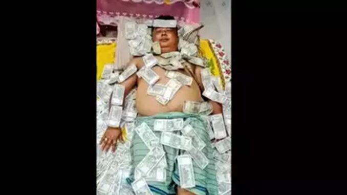 Basumatary asleep on a bed covered with ₹500 notes