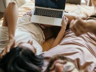 A Couple Lying on Bed Watching Netflix on Laptop