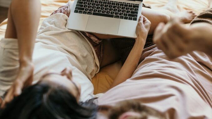 A Couple Lying on Bed Watching Netflix on Laptop